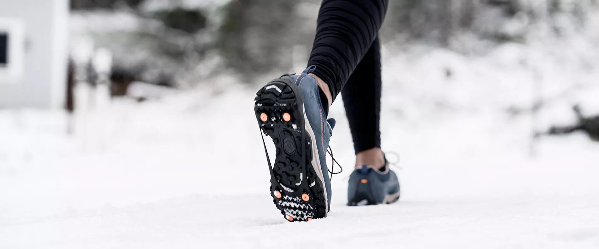 ild eines Laufschuhs mit Anti-Rutsch Schuh-Spikes in winterlicher Umgebung